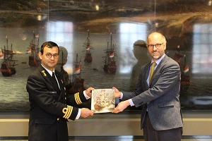 Voorzitter KVMO Rob Pulles ontvangt uit handen van Hoofd Collecties Jeroen van der Vliet de expositiecatalogus Willem van de Velde & Zoon